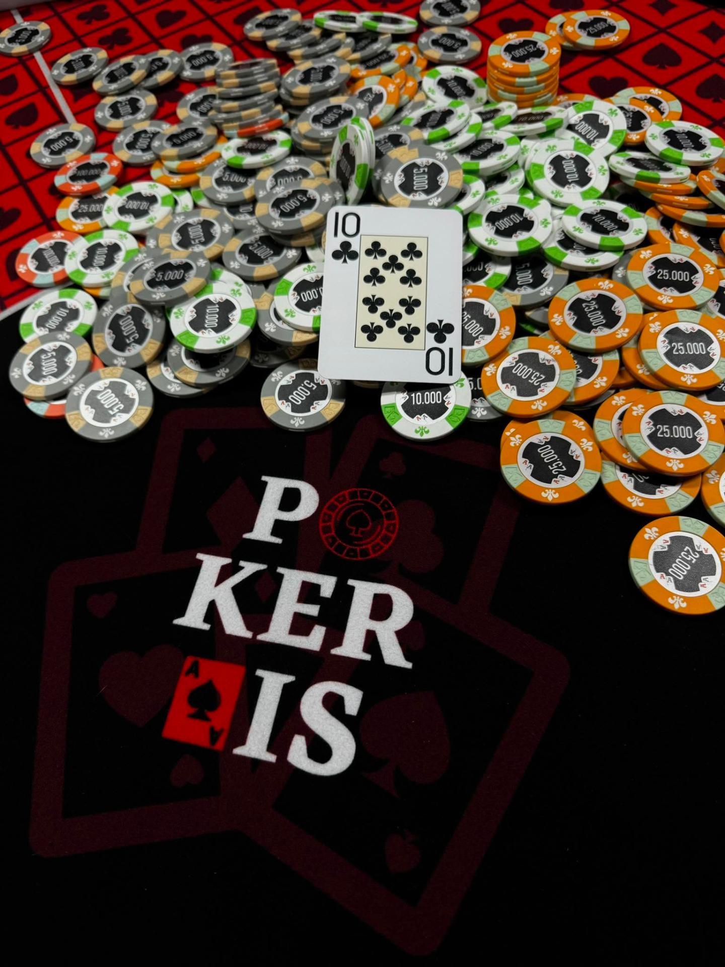 Pokerais firminių žetonų krūva ir kortos ant turnyrinio stalo